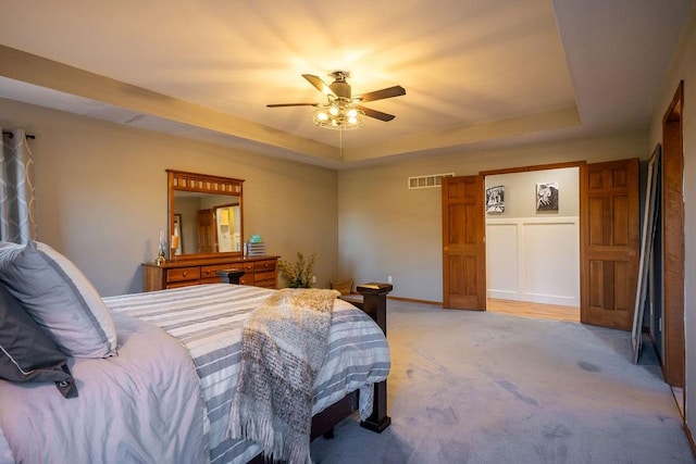 carpeted bedroom featuring a tray ceiling and ceiling fan