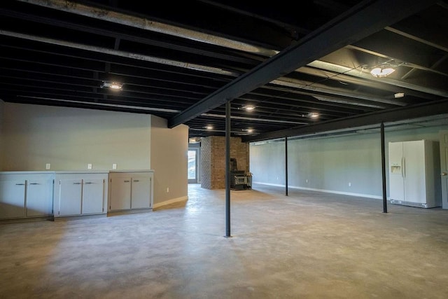 basement featuring a wood stove and white fridge with ice dispenser