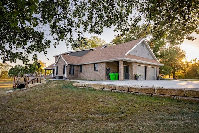 back house at dusk featuring a wooden deck, a garage, and a lawn