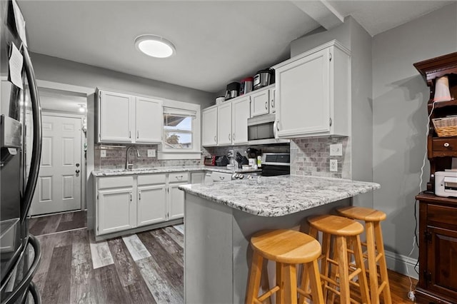 kitchen with tasteful backsplash, white cabinets, a breakfast bar area, and stainless steel appliances