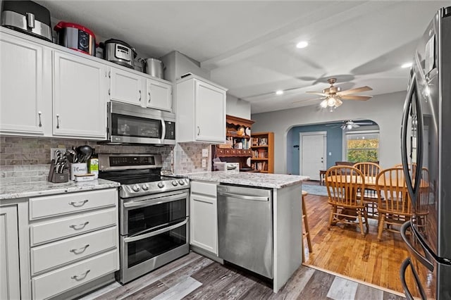 kitchen featuring white cabinetry, decorative backsplash, appliances with stainless steel finishes, and dark hardwood / wood-style flooring