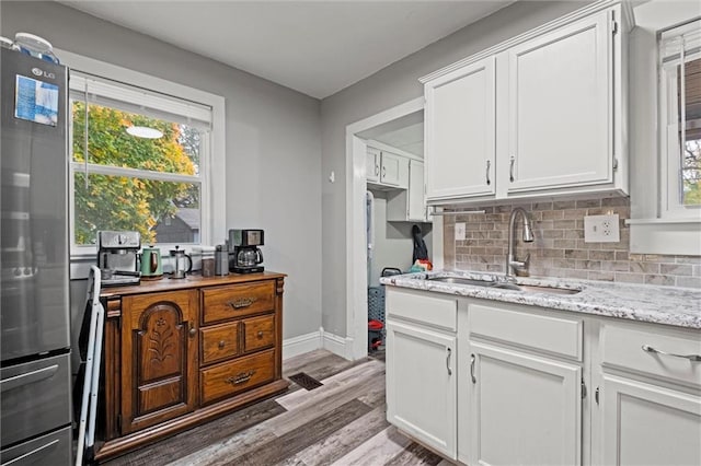 kitchen with white cabinets, plenty of natural light, sink, and stainless steel refrigerator