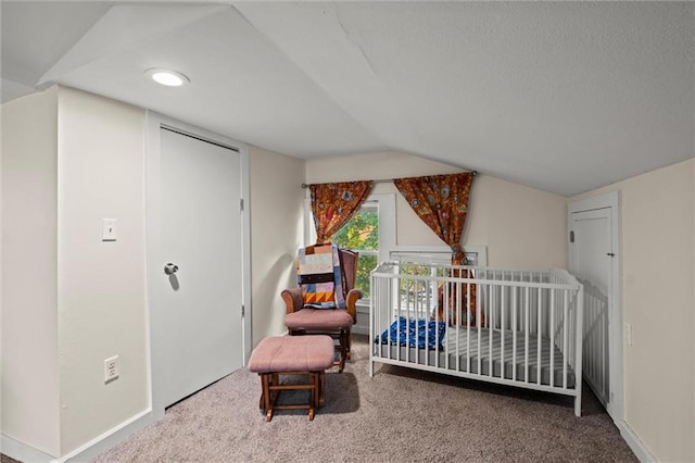 bedroom featuring a crib, lofted ceiling, and carpet