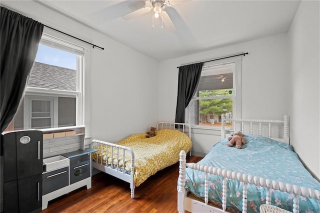 bedroom with dark hardwood / wood-style floors, ceiling fan, and multiple windows