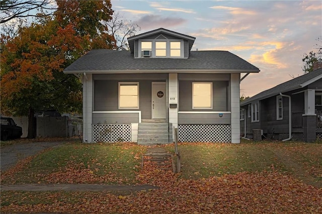 bungalow-style house featuring a lawn and central AC