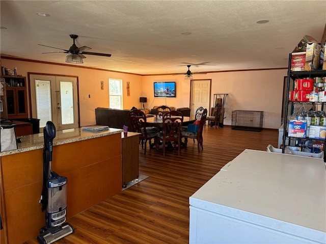 dining space with ceiling fan, dark wood-type flooring, french doors, ornamental molding, and a textured ceiling