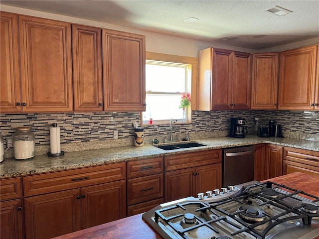 kitchen featuring light stone counters, dishwasher, backsplash, range with gas stovetop, and sink