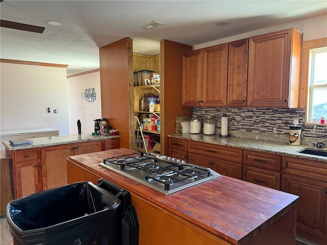 kitchen featuring sink, a center island, stainless steel gas cooktop, and butcher block counters