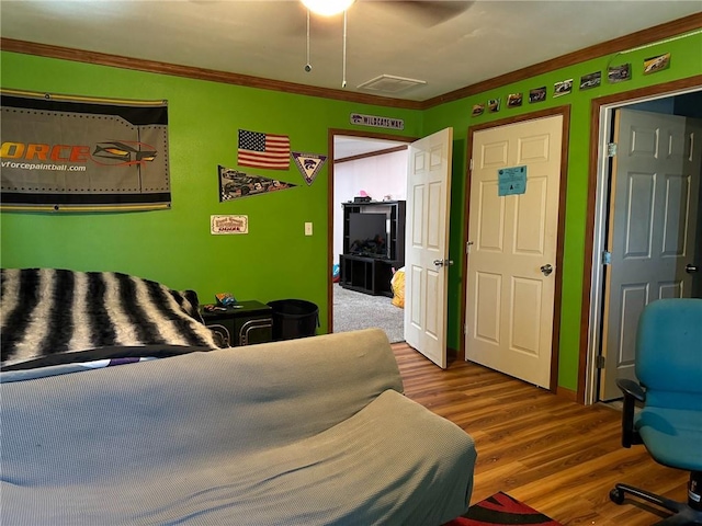 bedroom featuring hardwood / wood-style flooring, ceiling fan, and ornamental molding