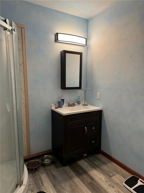 bathroom featuring walk in shower, wood-type flooring, and vanity