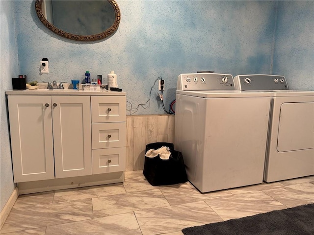 clothes washing area with wooden walls, cabinets, and independent washer and dryer