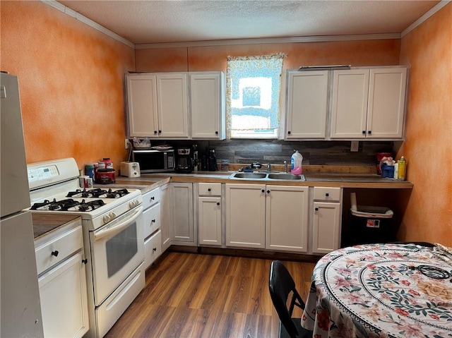 kitchen with gas range gas stove, dark hardwood / wood-style flooring, refrigerator, sink, and white cabinetry