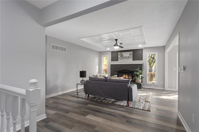 living room with ceiling fan, a raised ceiling, dark hardwood / wood-style flooring, and a fireplace