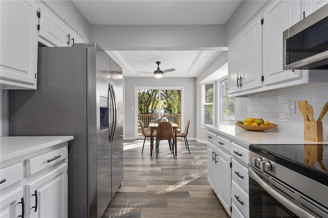 kitchen featuring stainless steel appliances, wood-type flooring, tasteful backsplash, white cabinets, and ceiling fan