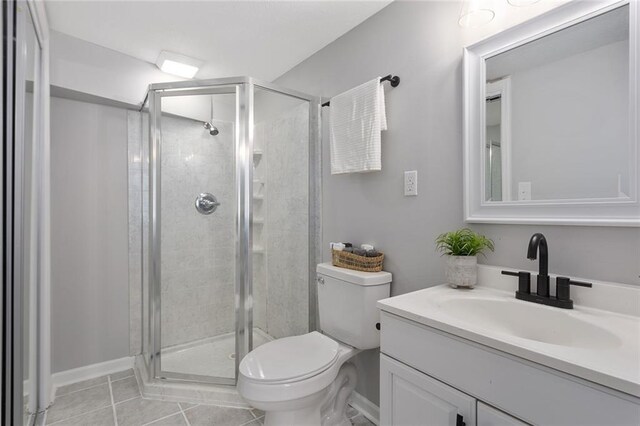 bathroom featuring vanity, toilet, walk in shower, and tile patterned flooring