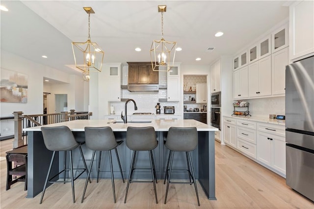 kitchen with white cabinetry, a large island with sink, stainless steel appliances, and hanging light fixtures