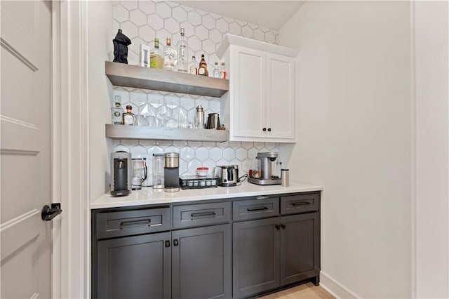 bar featuring white cabinetry, gray cabinetry, and backsplash