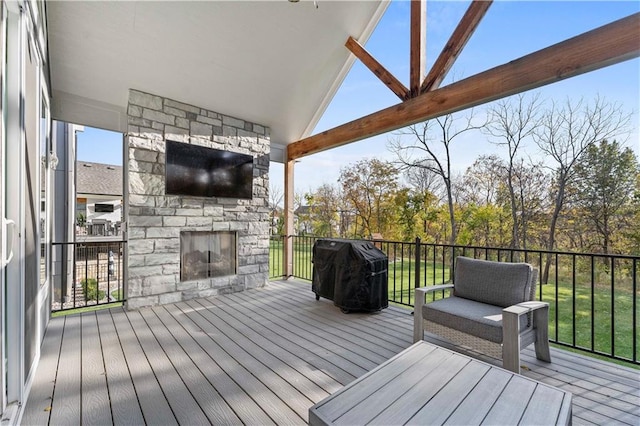 wooden deck with an outdoor stone fireplace and area for grilling