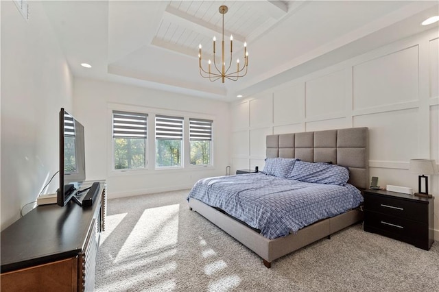 bedroom featuring light carpet, a tray ceiling, and a chandelier