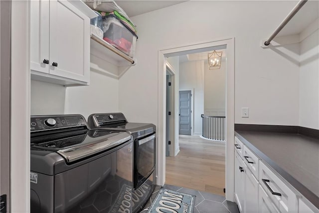 laundry area with cabinets, an inviting chandelier, dark wood-type flooring, and washing machine and clothes dryer