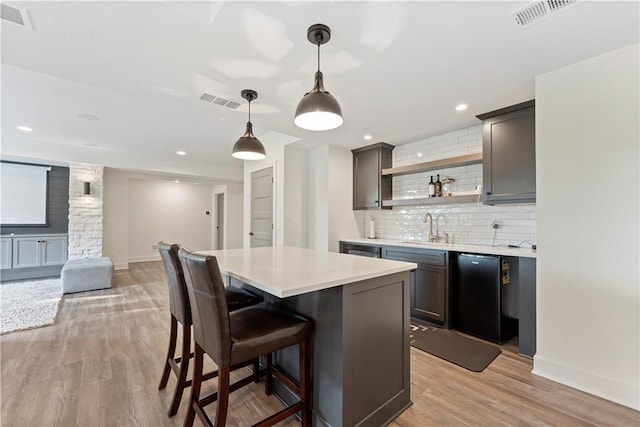 kitchen featuring light hardwood / wood-style floors, decorative light fixtures, sink, and a kitchen island