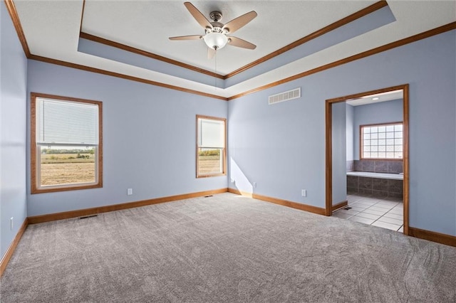 empty room with crown molding, light colored carpet, a raised ceiling, and ceiling fan