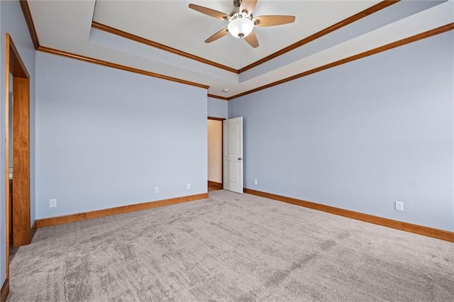 carpeted spare room with ceiling fan, ornamental molding, and a tray ceiling