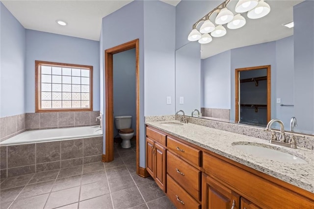 bathroom with vanity, a relaxing tiled tub, toilet, and tile patterned flooring