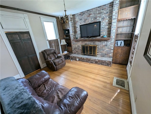 living room featuring a notable chandelier, hardwood / wood-style floors, a fireplace, and built in features