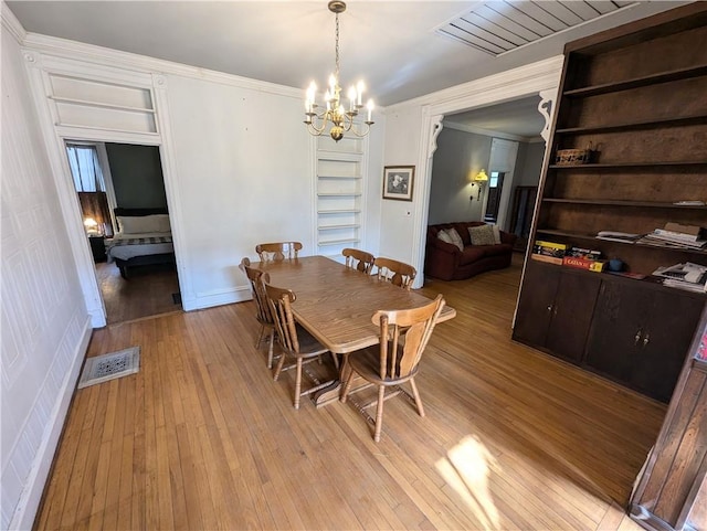 dining space featuring crown molding, a notable chandelier, and light wood-type flooring