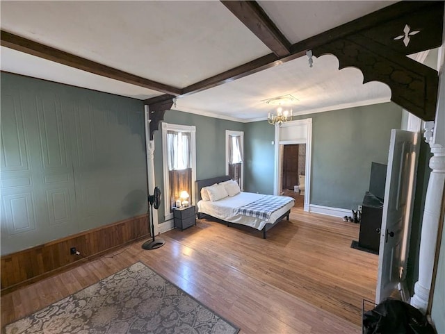 unfurnished bedroom with beam ceiling, a chandelier, ornamental molding, light hardwood / wood-style floors, and wooden walls