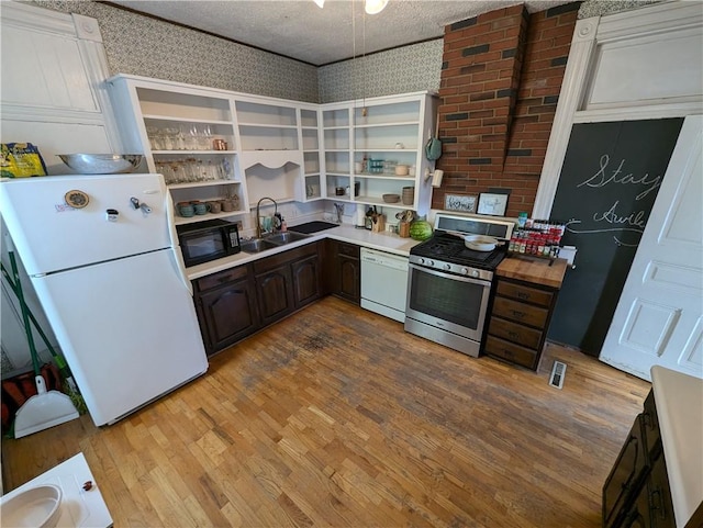 kitchen with light hardwood / wood-style flooring, a textured ceiling, dark brown cabinets, and white appliances