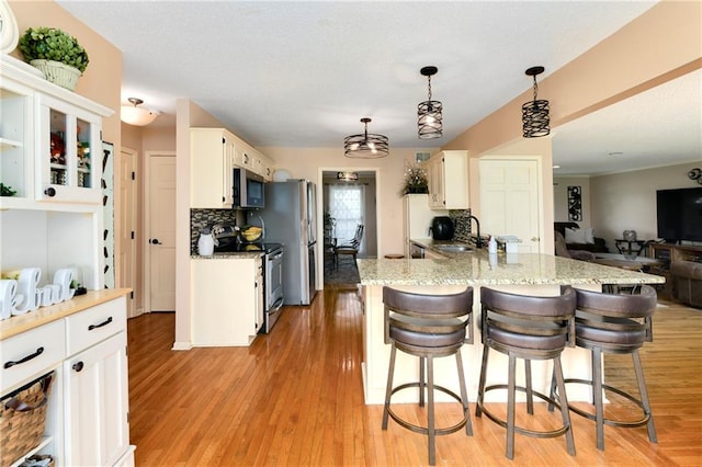 kitchen featuring white cabinets, stainless steel appliances, and decorative light fixtures