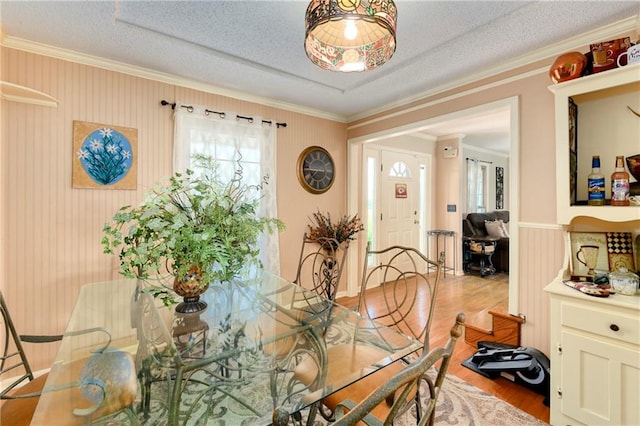 dining area with crown molding, a textured ceiling, and light hardwood / wood-style floors