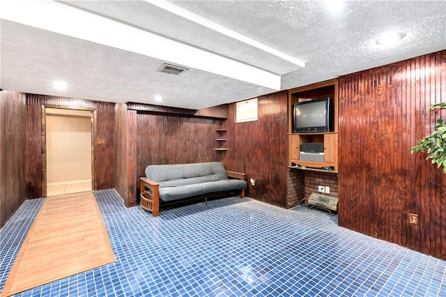 sitting room with wood walls, a textured ceiling, and light wood-type flooring