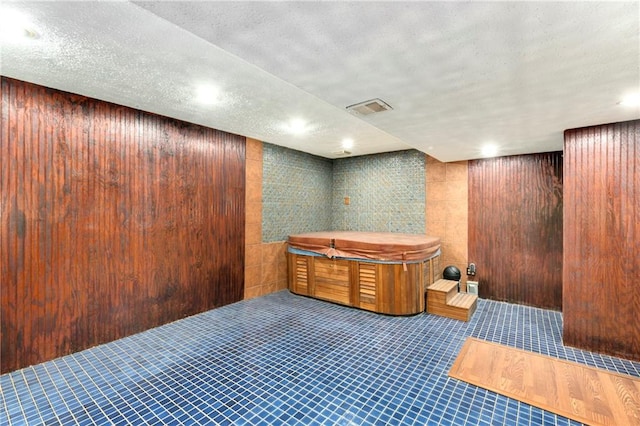 misc room with wood walls, a textured ceiling, and a jacuzzi