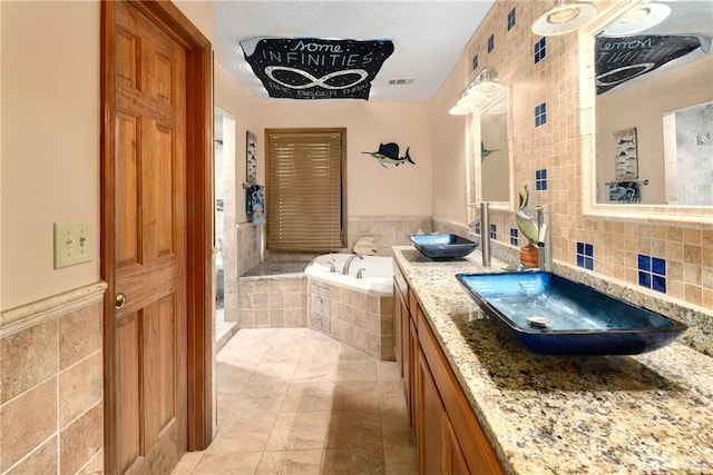 bathroom featuring vanity, a relaxing tiled tub, tile patterned floors, and tile walls