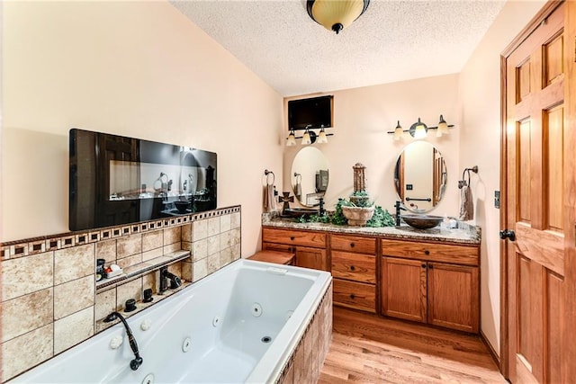 bathroom featuring vanity, a textured ceiling, wood-type flooring, and a bathtub