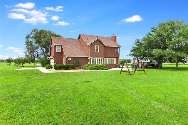 rear view of house with a yard and a playground