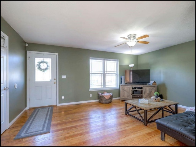 living room with light hardwood / wood-style floors, ceiling fan, and a healthy amount of sunlight