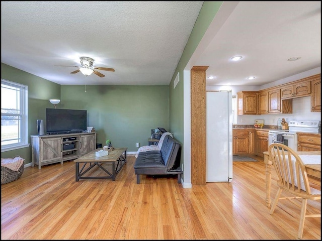 living room with ceiling fan, a textured ceiling, and light hardwood / wood-style flooring