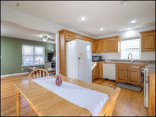 kitchen featuring ceiling fan, white appliances, sink, and light hardwood / wood-style flooring