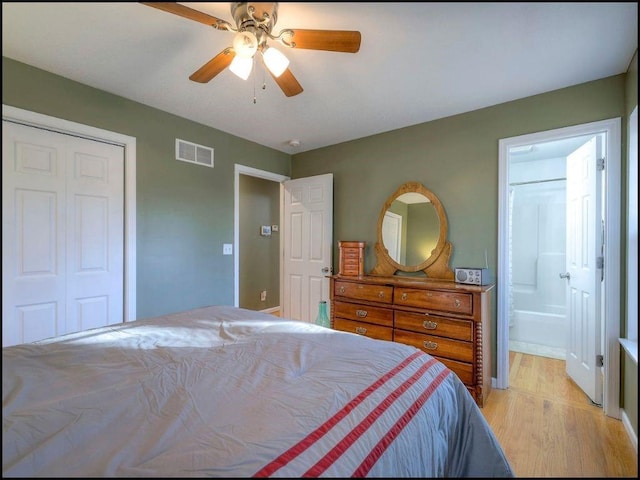 bedroom with ceiling fan, light hardwood / wood-style floors, ensuite bath, and a closet