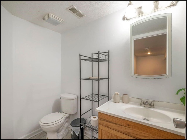 bathroom featuring vanity, toilet, and a textured ceiling