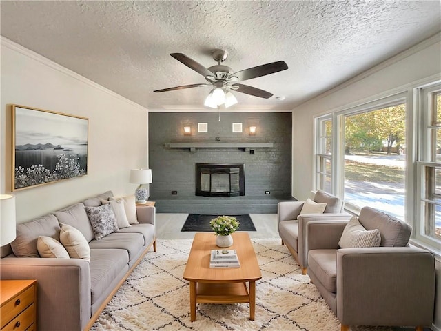 living room featuring crown molding, a brick fireplace, a textured ceiling, and ceiling fan