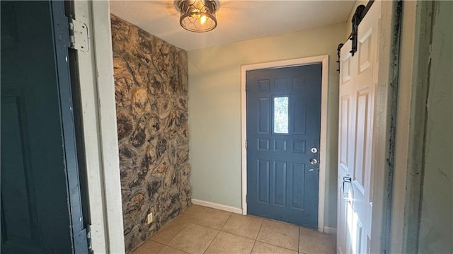 tiled foyer with a barn door and ceiling fan