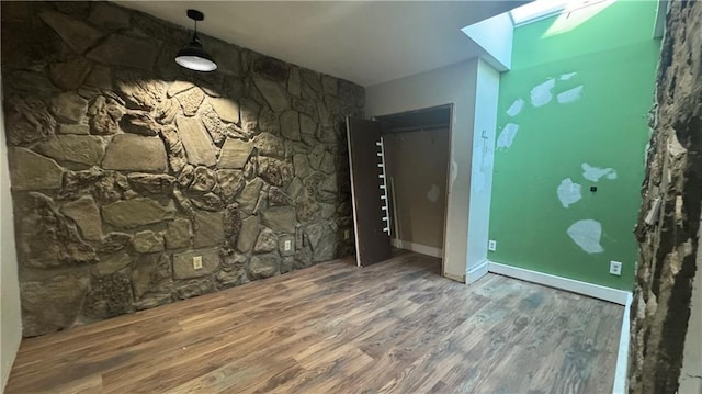 unfurnished room featuring a skylight and hardwood / wood-style floors