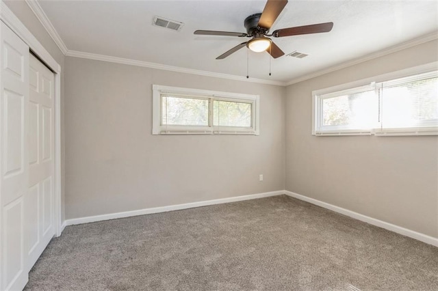 empty room featuring carpet, plenty of natural light, ceiling fan, and crown molding