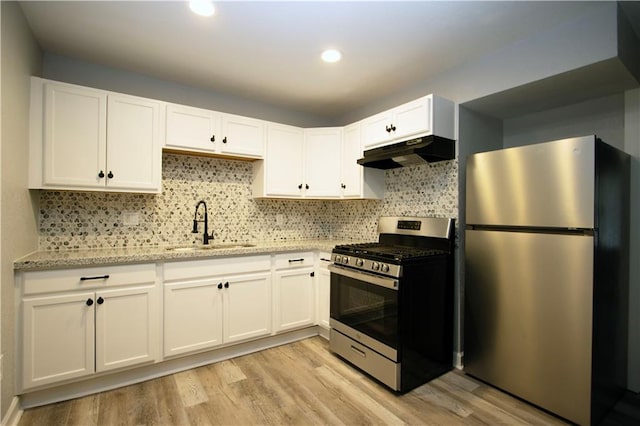 kitchen with sink, appliances with stainless steel finishes, backsplash, white cabinets, and light wood-type flooring