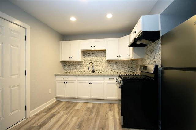 kitchen featuring sink, appliances with stainless steel finishes, white cabinets, light wood-type flooring, and decorative backsplash